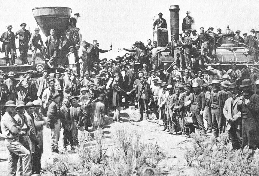 a wider view of the golden spike ceremony at promontory, utah, showing the two locomotives facing each other and the crowd gathered for the celebration