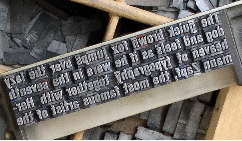 A close view of individual pieces of movable metal type arranged for printing