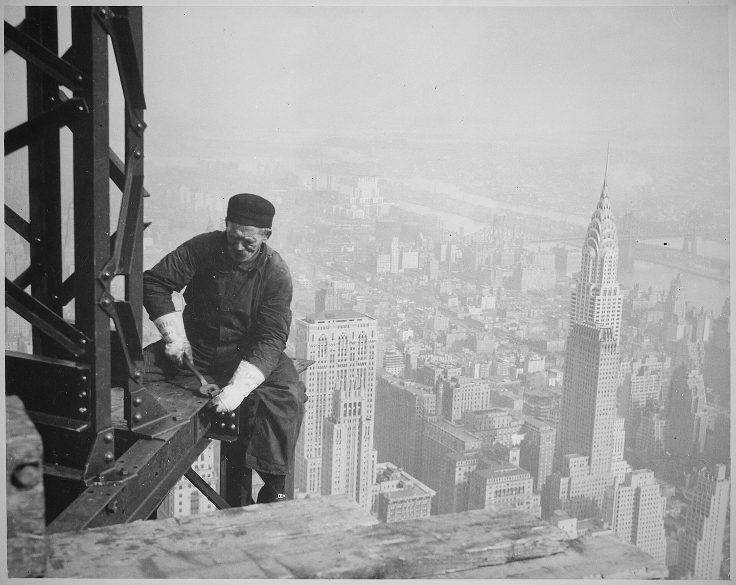 a workman standing on the steel framework of the empire state building during construction