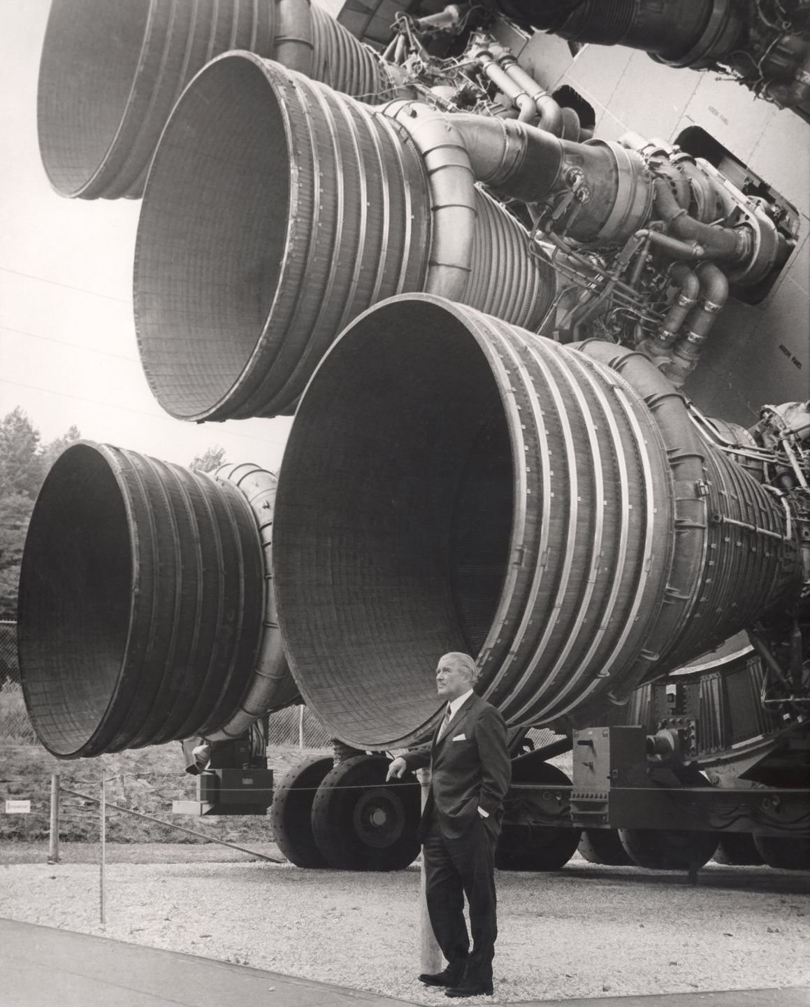 Wernher von Braun standing beside the five F-1 engines of a Saturn V first stage