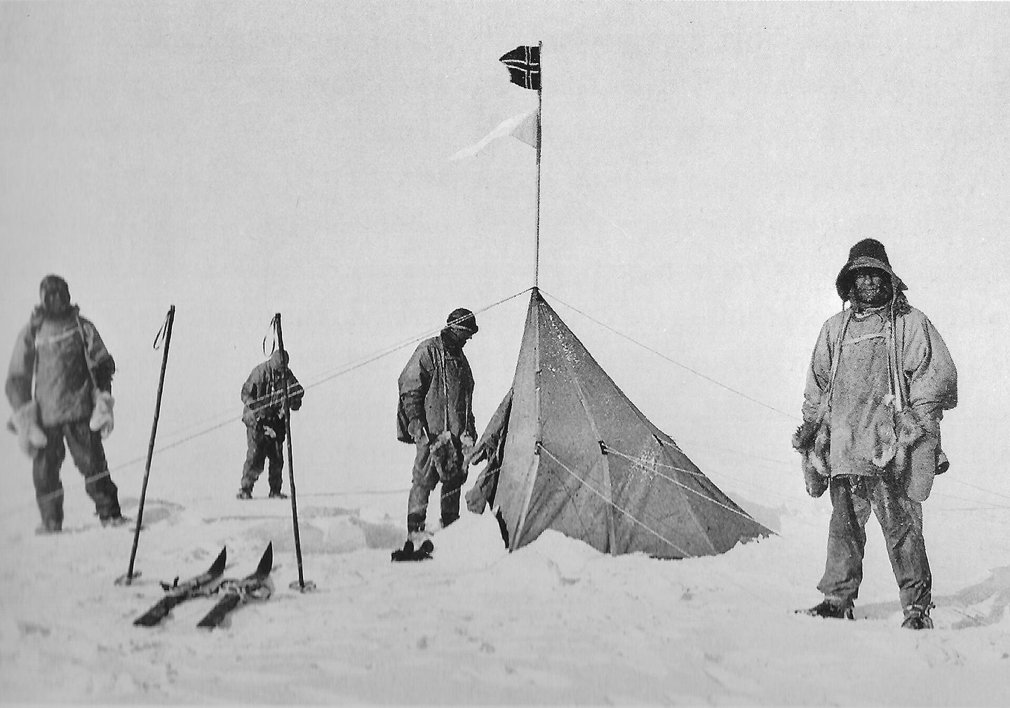 members of scott's expedition standing at amundsen's tent and norwegian flag at the south pole
