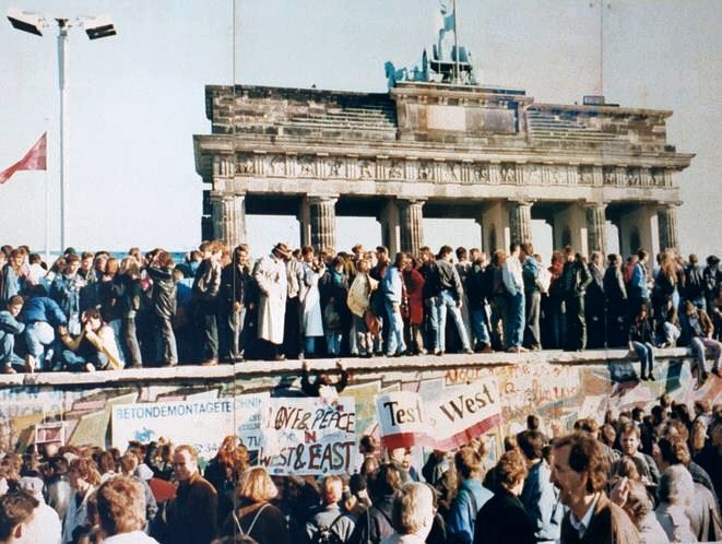 People standing on the Berlin Wall near the Brandenburg Gate on November 9, 1989